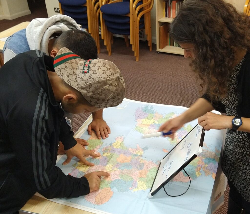 Two After18 service users examine a map with an After18 volunteer during a weekly education drop-in session.