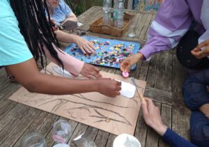 Young women glue buttons signifying fruits to a drawing of a tree, as part of an activity organised for the young women's group