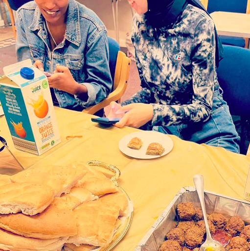 Two young women smile together as they share some freshly cooked food during the young women's support group